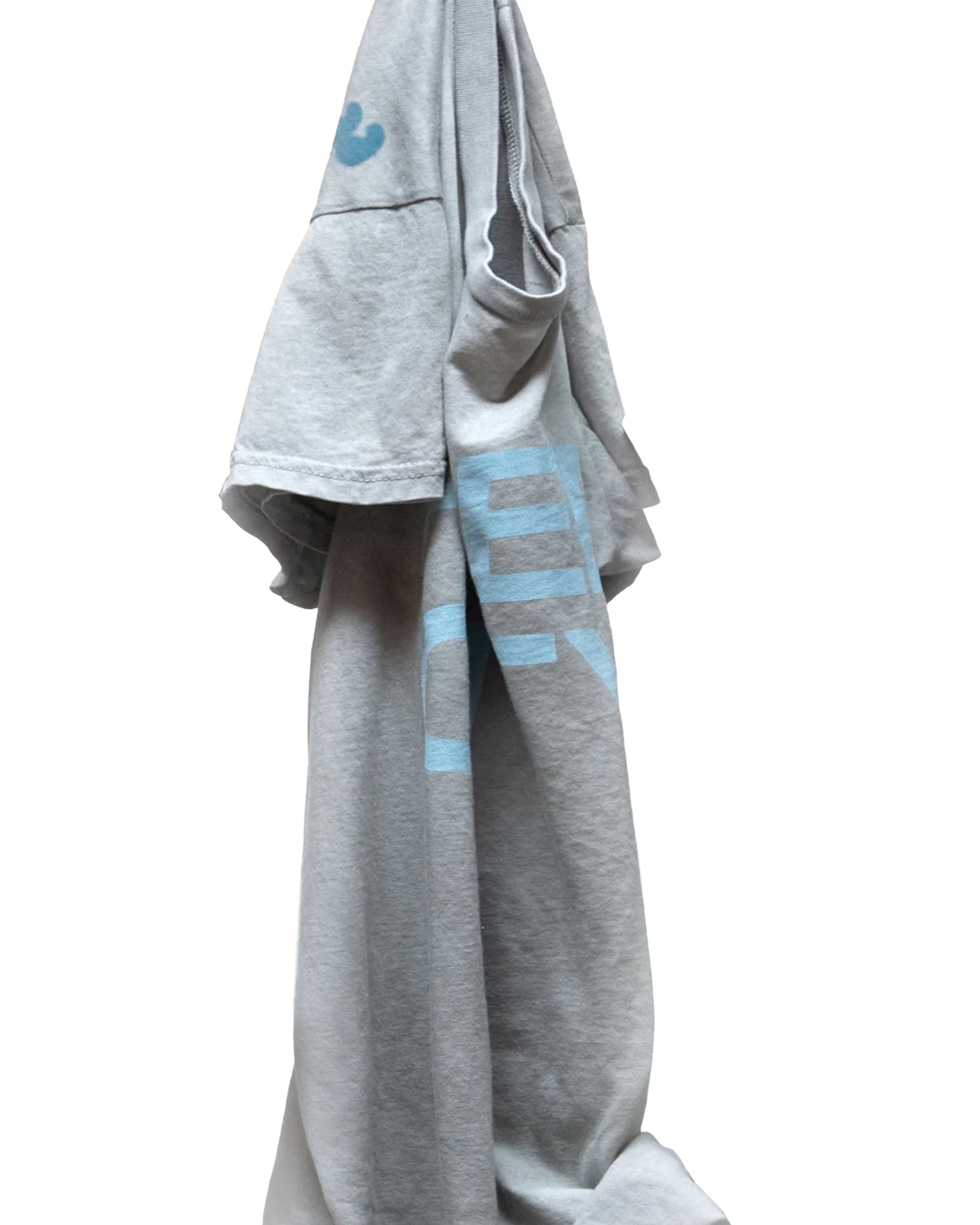 A light gray Free City FC thedoingofitis... SS Tee with blue graphics hangs on a hook against a white background. Casually draped, it shows off its custom sunfade dye, with one sleeve facing out and the lower hem hanging down.
