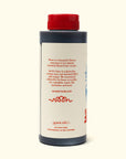 A plastic bottle with a red cap contains Faire’s Woon Stir Fry Sauce, a gluten-free cooking sauce. The label gives usage tips, shaking and refrigeration advice, website info, and is ideal for stir-fries or marinades.