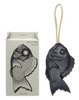 The Faire Tamanohada Soap, shaped like a black fish and featuring a hanging rope, is shown beside its box with a matching fish illustration and "WELCOME SOAP" text. This elegant soap is crafted from plant-based ingredients.