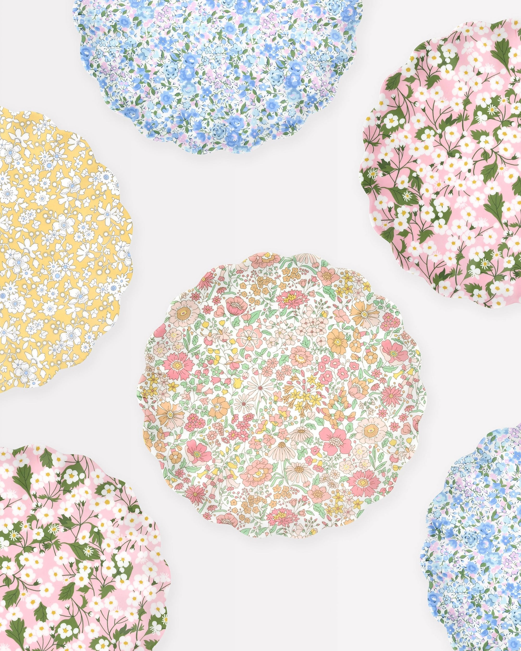 Six Faire Mixed Set Reusable Small Plates feature scalloped edges and unique Liberty print floral designs in pastel yellow, pink, blue, and green tones, arranged on a light background.