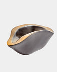 The Formation bowl by Global Views is a modern Italian ceramic piece with smooth curves, an organic shape, a matte black exterior, and a gold-toned rim, displayed against a plain white background.