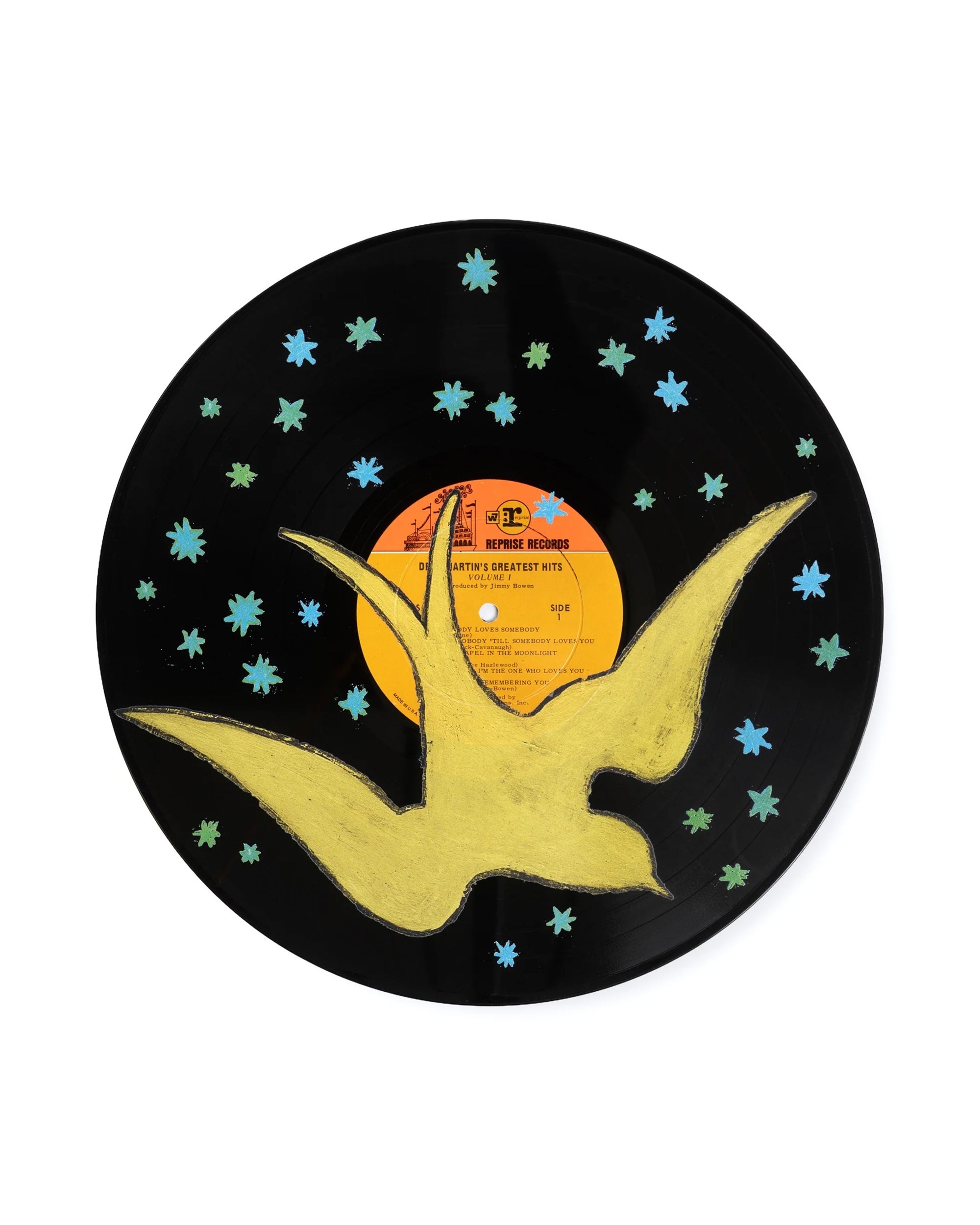 The Free Bird Vinyl Record by Sugarboo Designs features a black vinyl disc with a yellow bird in flight, blue-green stars, and an orange label, creating a playful and charming wall decor piece.