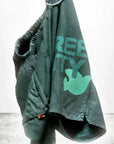 A pair of green Free City Matte/Satin BackPocket Shorts with an elastic waistband hangs on a hook. Handmade in Los Angeles, these shorts feature a dove graphic and partial "REE TY" text in light green.