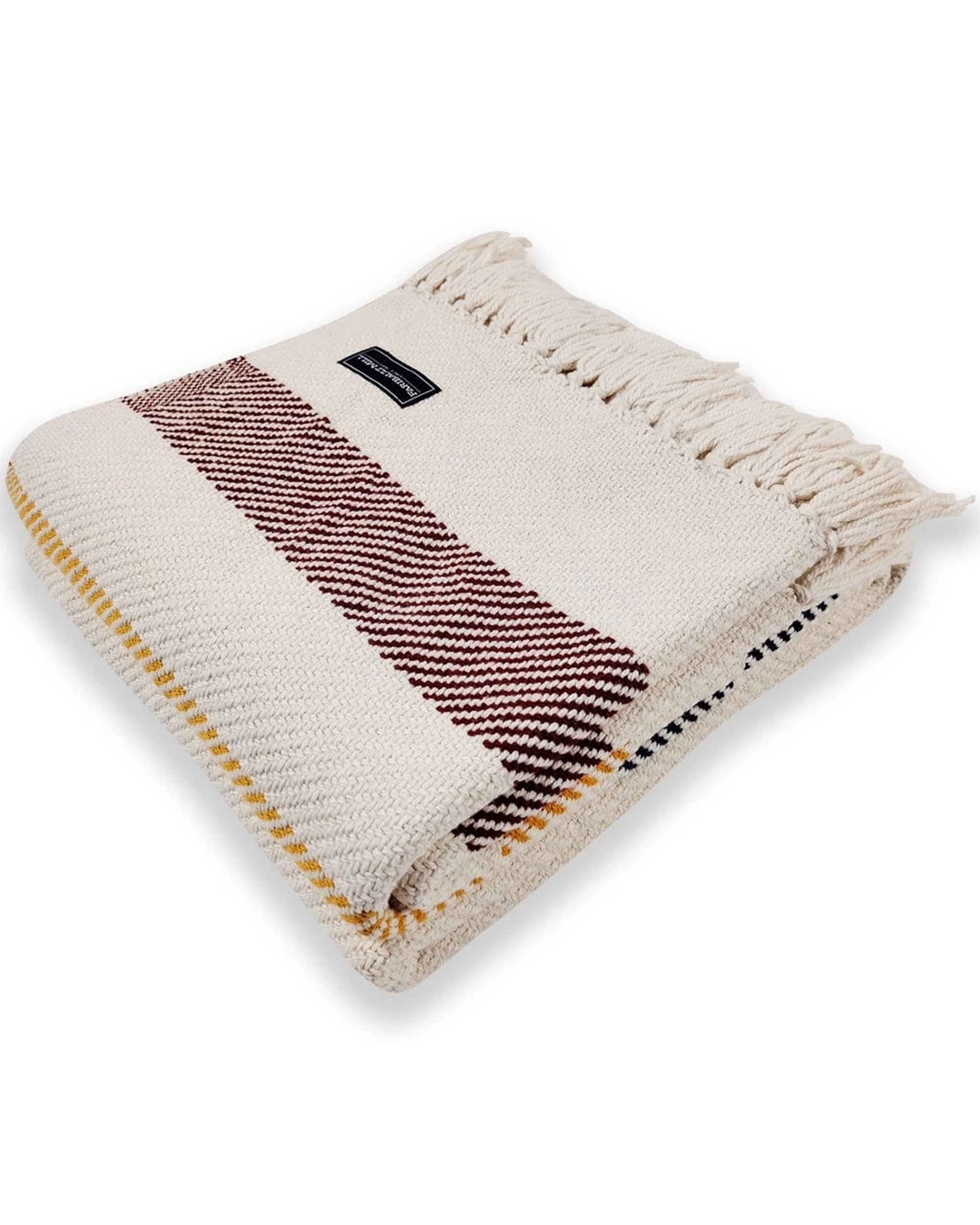 A folded cream-colored Faire Frontier Cotton Throw with brown and yellow stripes, fringed edges, and a black fabric label is shown on a white background.