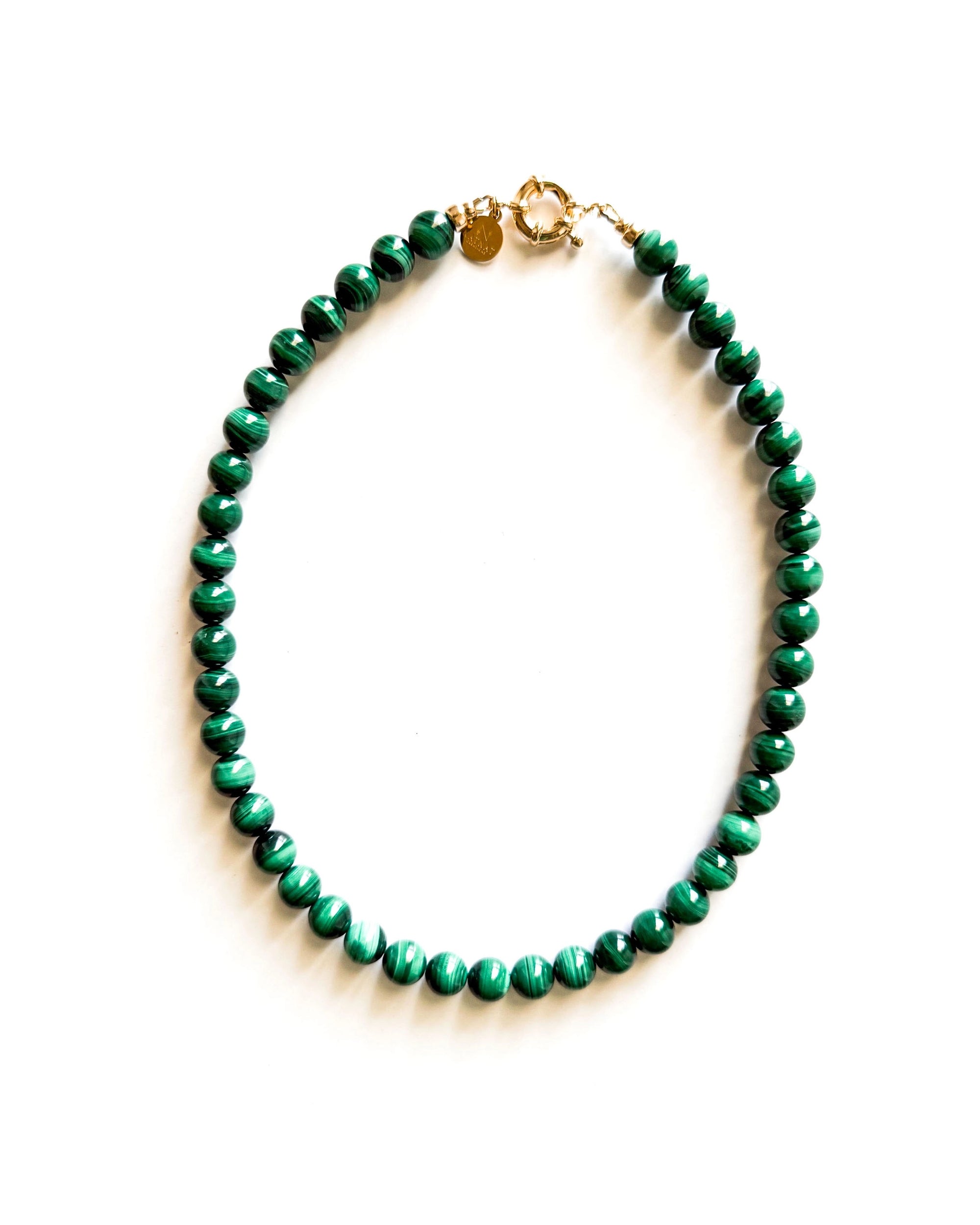 The Galleria Necklace by Faire is a 17-inch piece with green round malachite beads and gold-plated findings, displayed in a circle on a white background.