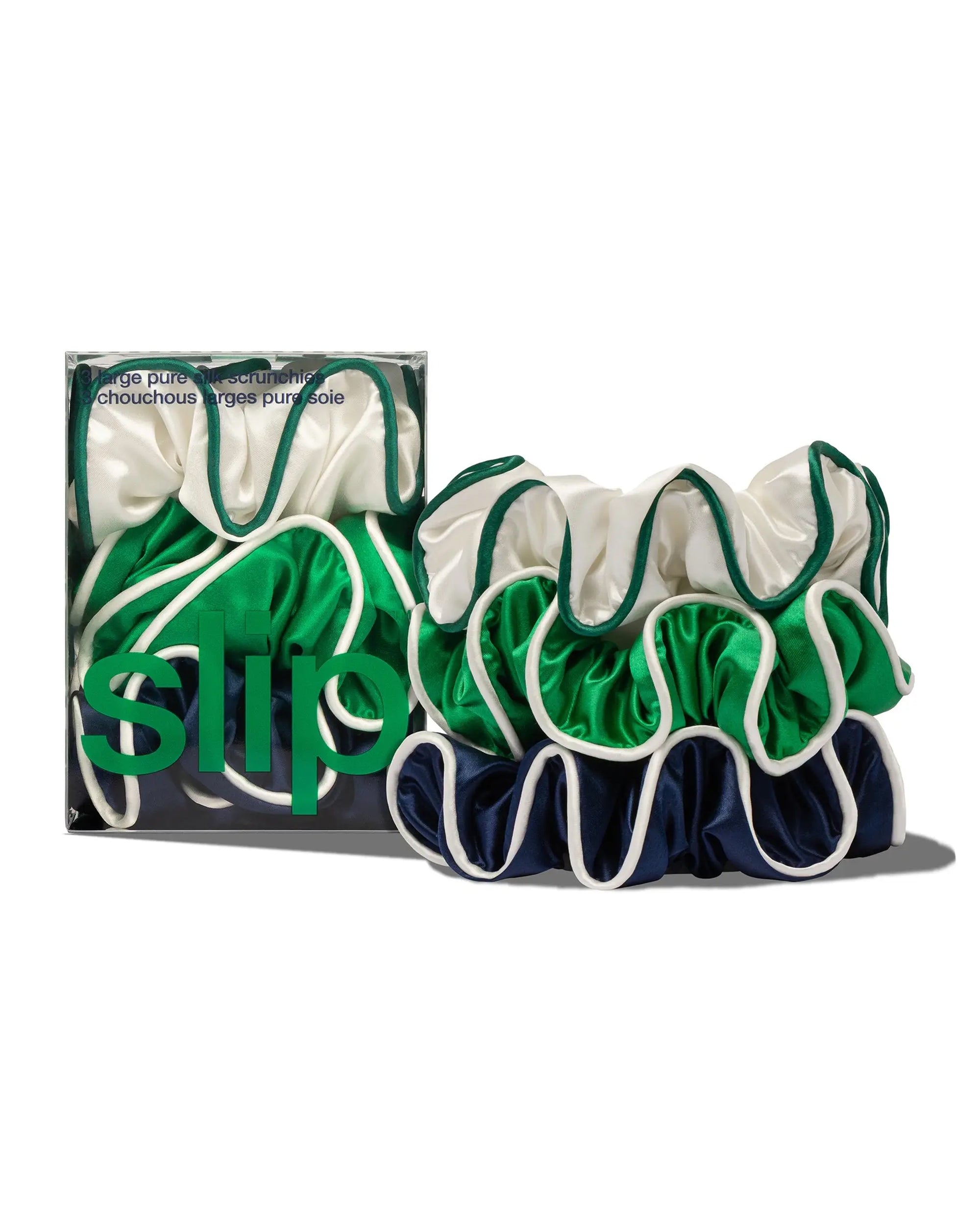Three large Game Day Large Scrunchies by Faire in green, white, and navy with wavy edges are shown beside a "slip" box. These silk scrunchies help prevent hair breakage while giving your hair a stylish boost.