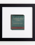 A framed book titled "GARDEN & GUN CLUB" displayed on a white wall. The book cover is dark green with a red spine, and the title is in uppercase letters with Match South Art Square Black Frames.