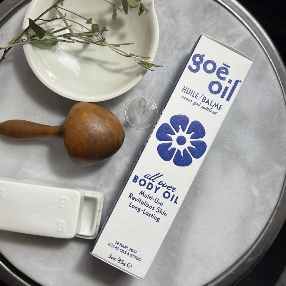 A box of Goe Oil by Jao Limited sits on a round marble tray with a wooden massager, white dish, and glass dropper—ideal for moisturizing skin and enhancing hair rejuvenation.