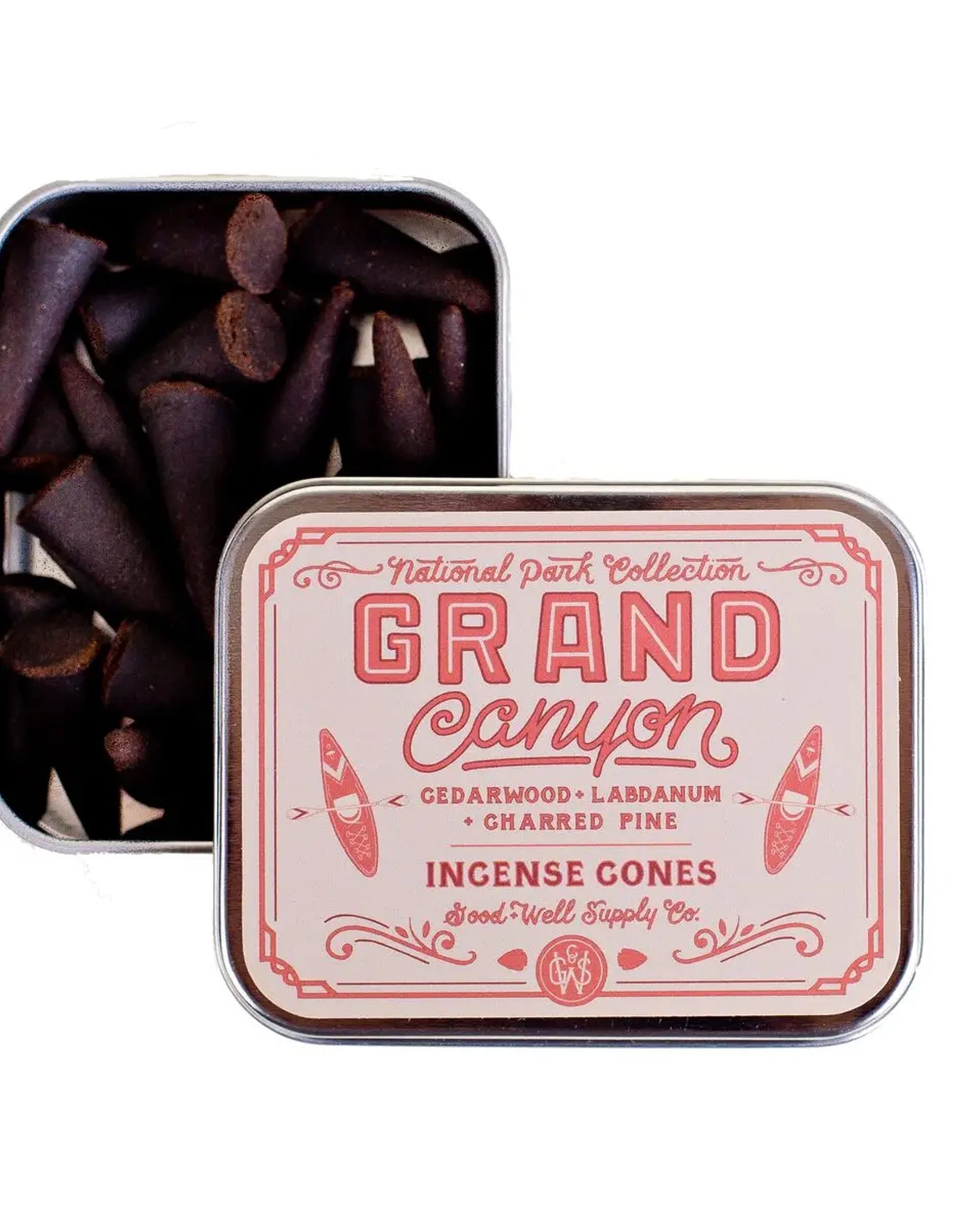 An open tin of G&W Incense by Faire with a pink and red design reveals dark brown cones. The label notes cedarwood, labdanum, and charred pine scents for an earthy incense experience.
