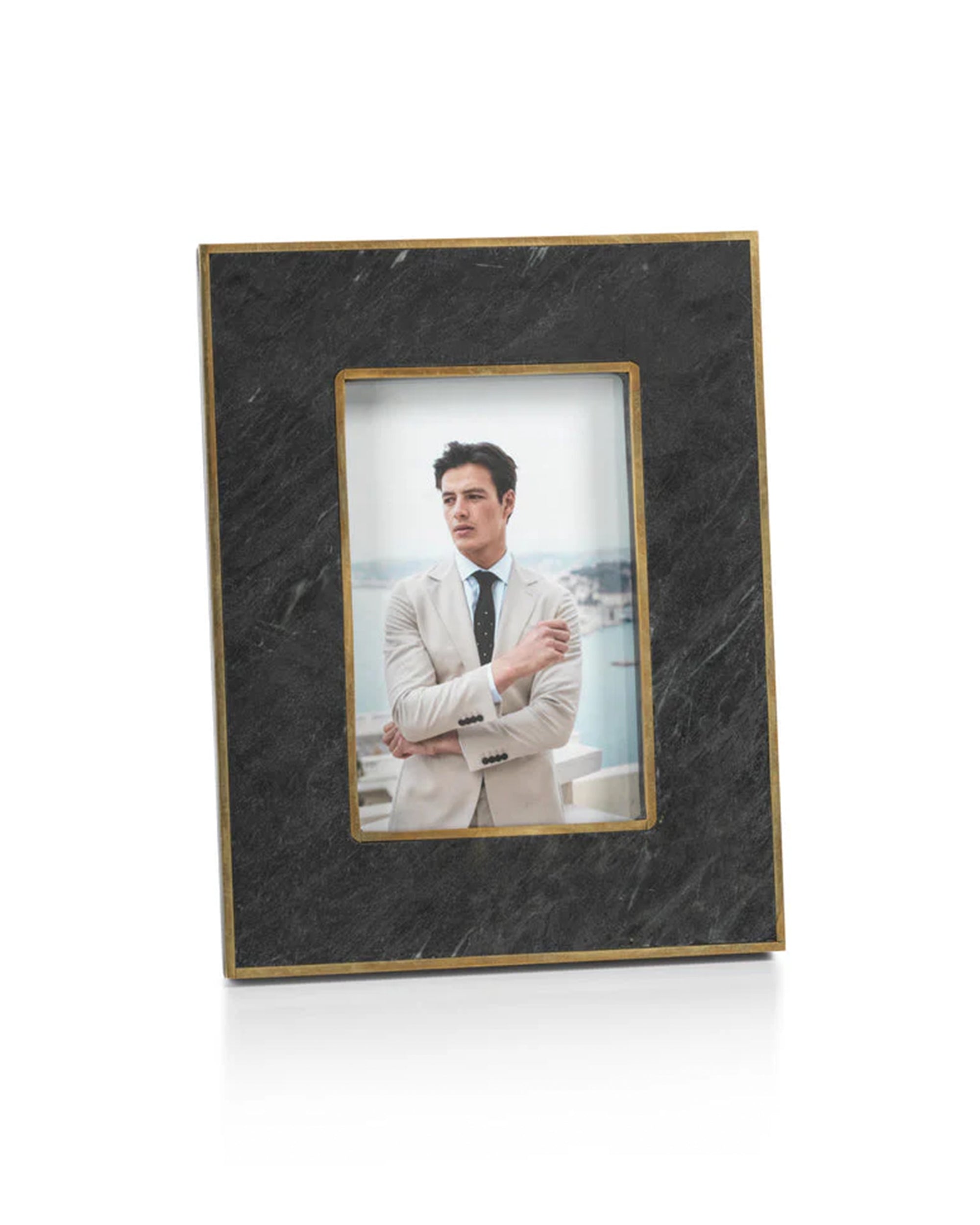 The Zodax IN-7596 Granite Photo Frame 4x6 elegantly displays a portrait of a man in a light suit and tie, standing outdoors with a cityscape in the background.