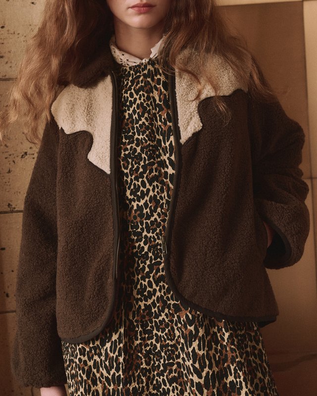 Close view of a brown jacket with a cream Western yoke layered over a leopard-print dress.