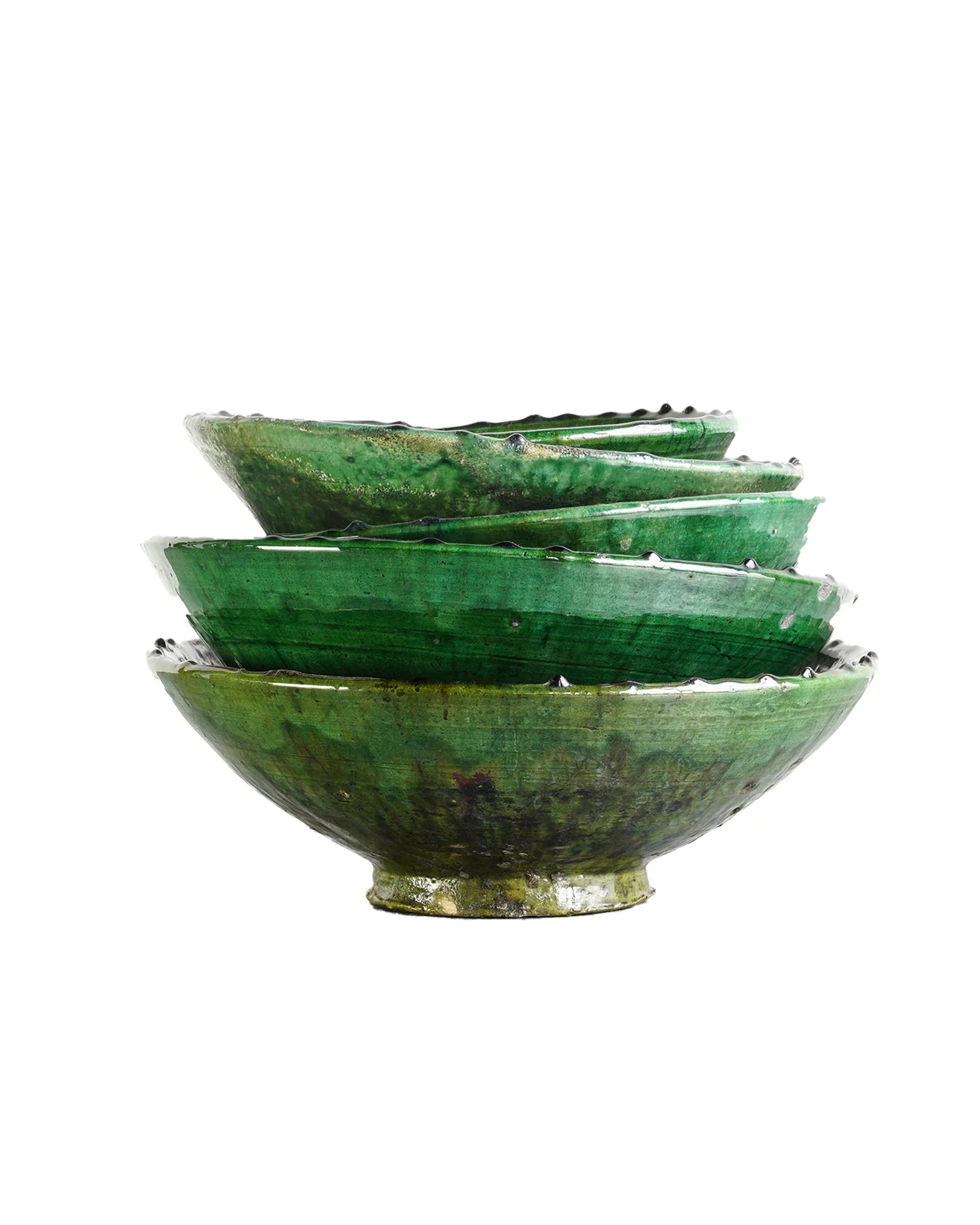 A set of four green, hand-crafted Tamegroute Bowls by Blue Ocean Traders with wavy edges creates a striking decorative accent against a white background.