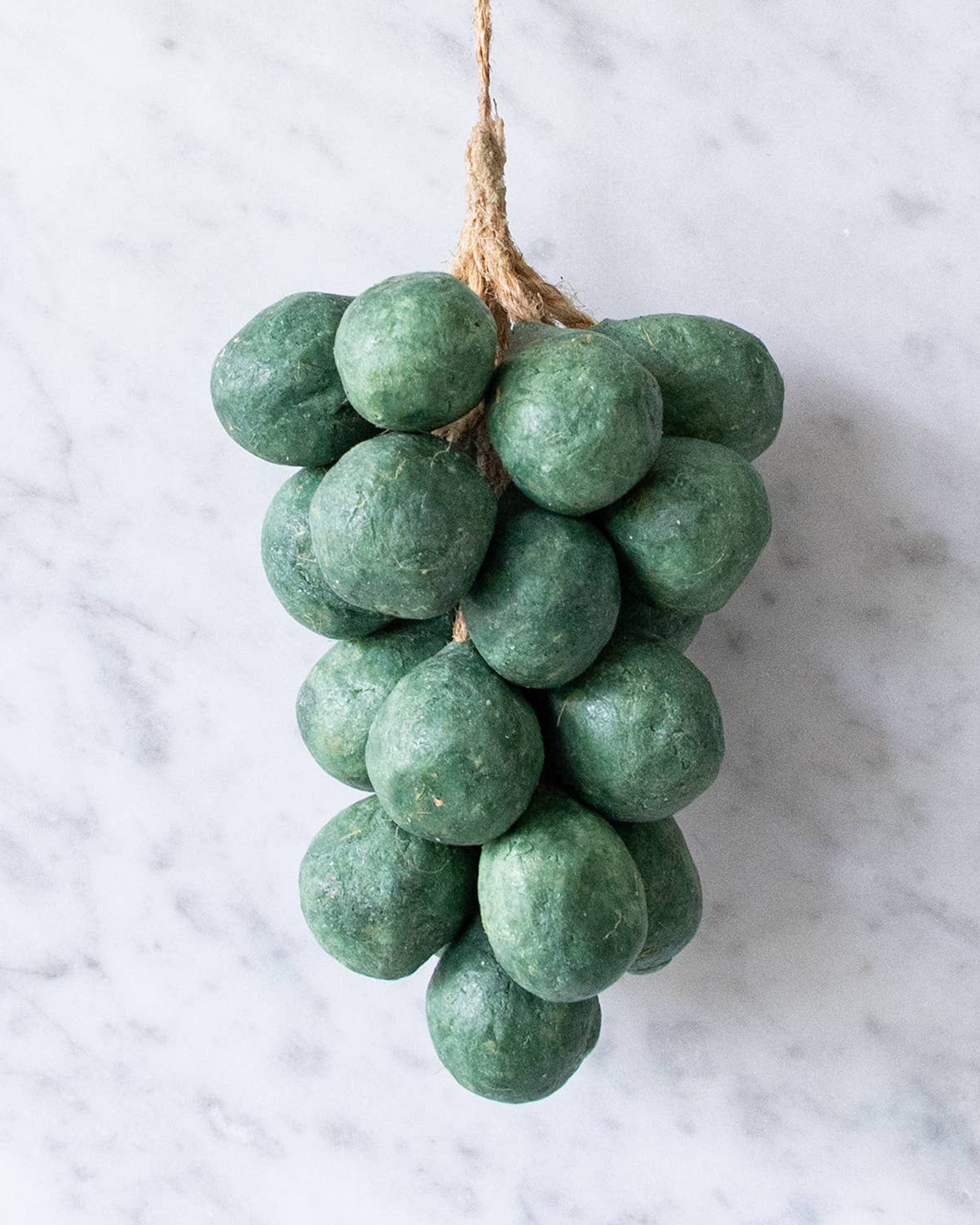 Faire's Handcrafted Grapes Soap features green, round, vegan soap balls tied with twine and displayed on a light marble background.