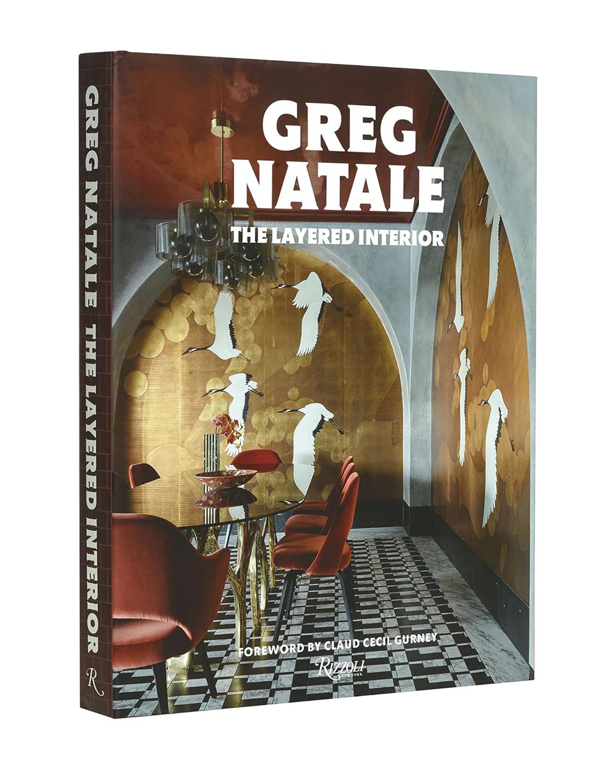 Greg Natale The Layered Interior" by Random House is a hardcover book showcasing stunning interior design with gold wall art, bird silhouettes, a red chair, round table, and chandelier—ideal inspiration for home decor enthusiasts.