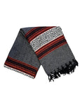 The Authentic Mexican Blanket Ember/Grey by Faire is a handmade, dark gray woven blanket with red and white stripes and black fringe—perfect as a stylish yoga prop or cozy home accent.