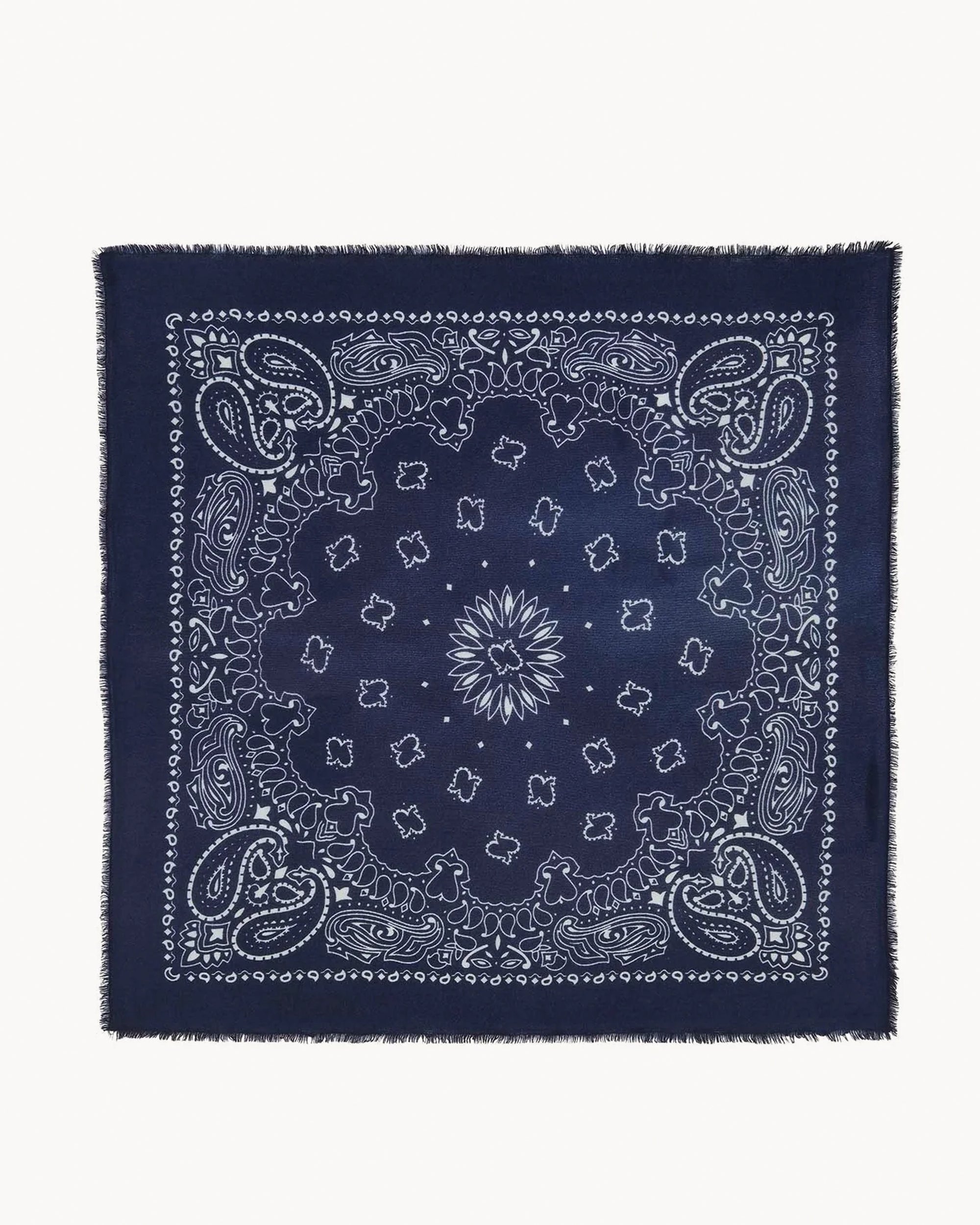 The Hachiko Scarf by BCS Group is a navy blue accessory with a white paisley and floral design arranged symmetrically, and fringed edges that evoke the look of a classic printed cashmere scarf.