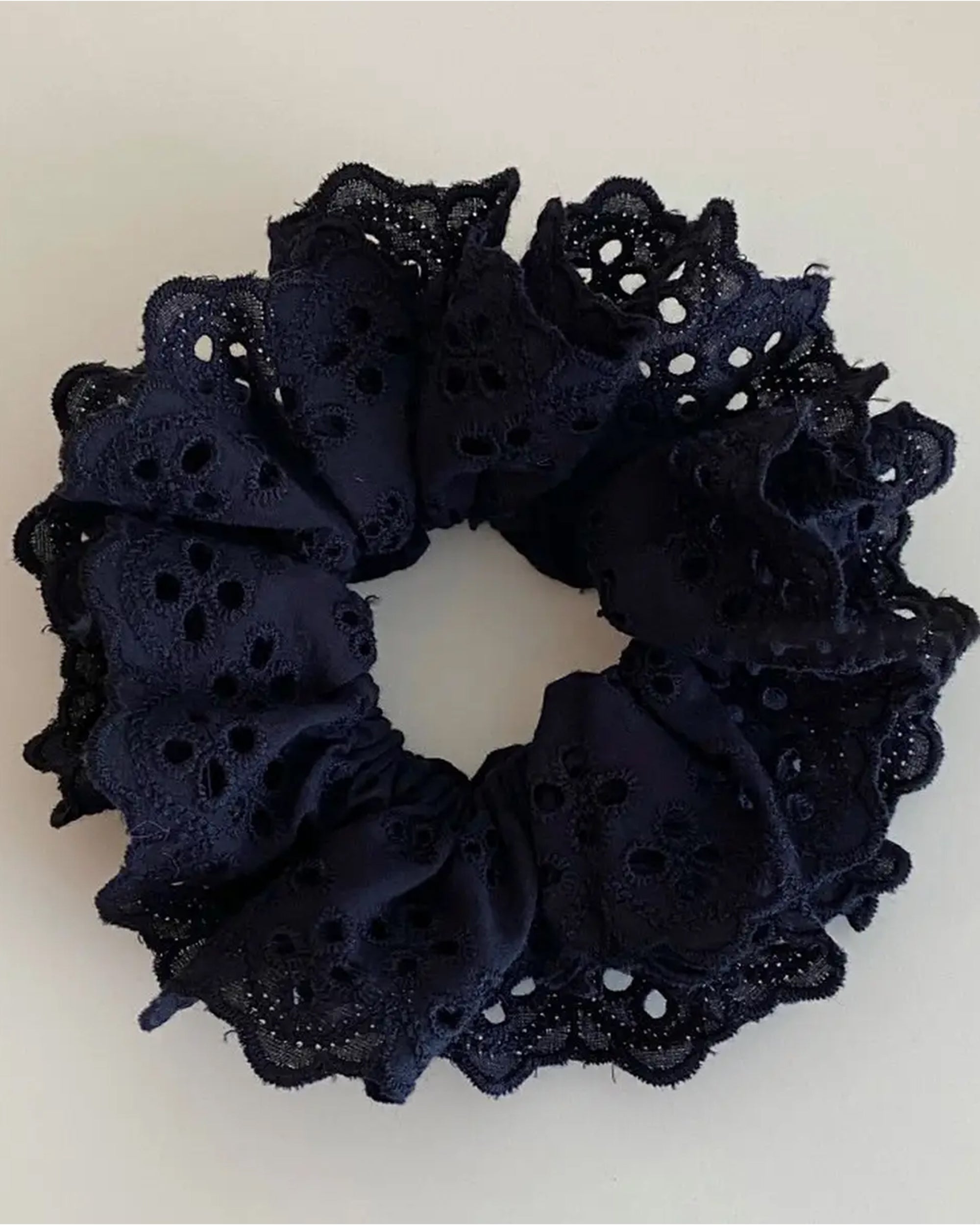 The Faire Hair Scrunchies feature black fabric with ruffled eyelet lace, displayed on a light background—ideal for those who love elegant lace hair accessories.