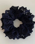 The Faire Hair Scrunchies feature black fabric with ruffled eyelet lace, displayed on a light background—ideal for those who love elegant lace hair accessories.