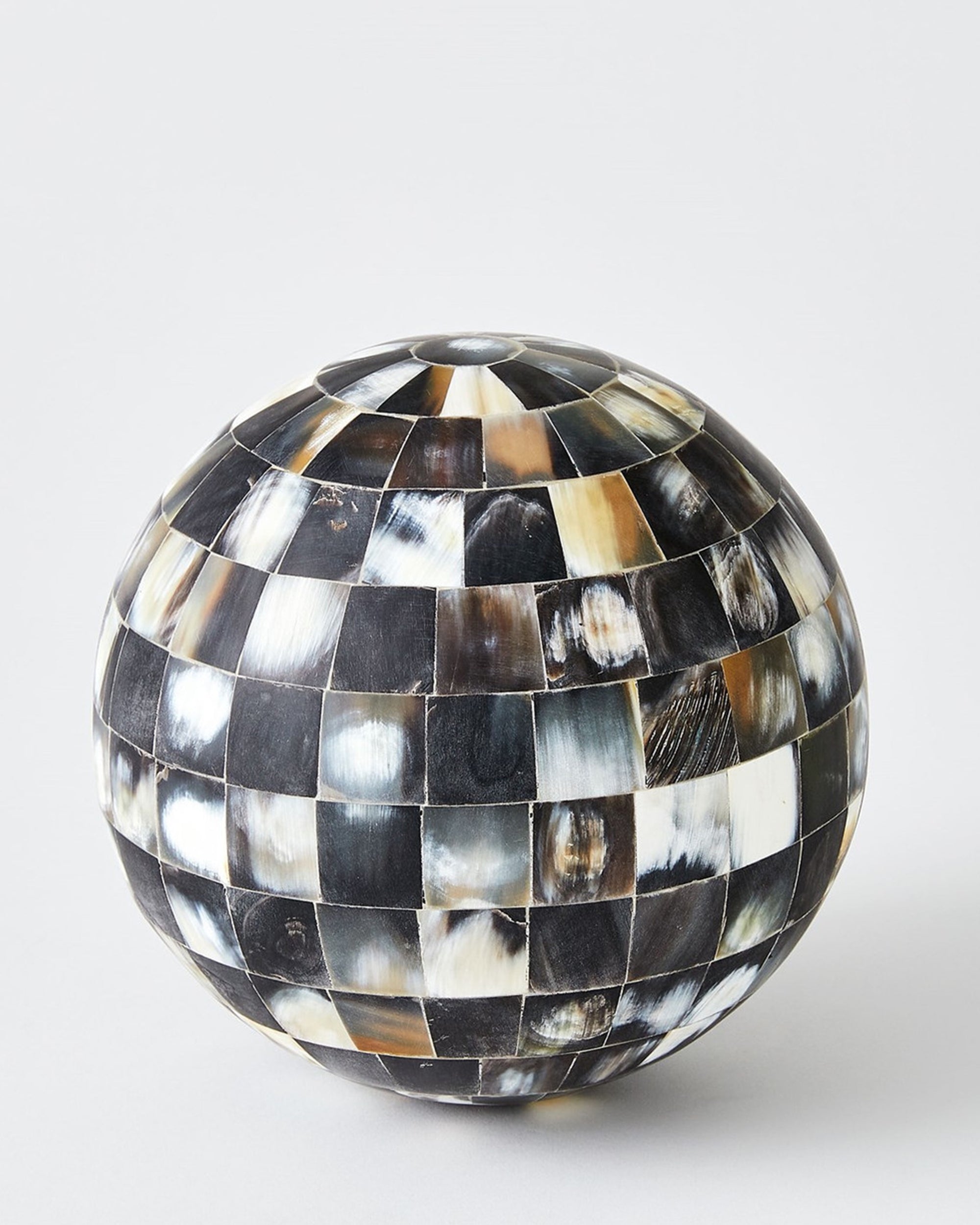 The Global Views 9.93947 Horn Sphere L features small, square tiles in black, white, brown, and gray checkerboard pattern. This glossy round accent adds a striking touch of luxury to your home decor.