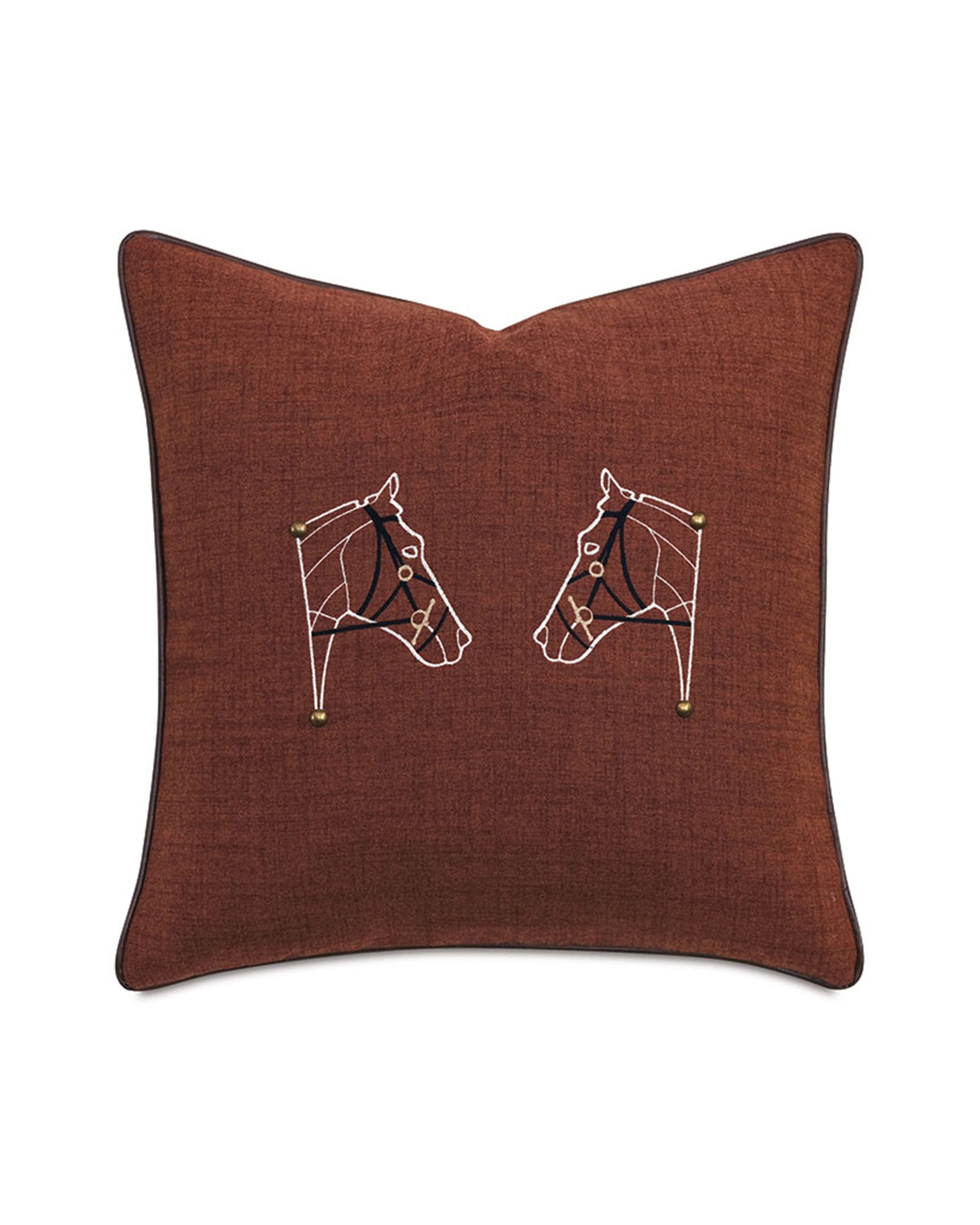 The EQUESTRAIN decorative pillow by Eastern Accents is square and brown with black piping, featuring two white embroidered horse heads with gold accents facing each other on a plain background.