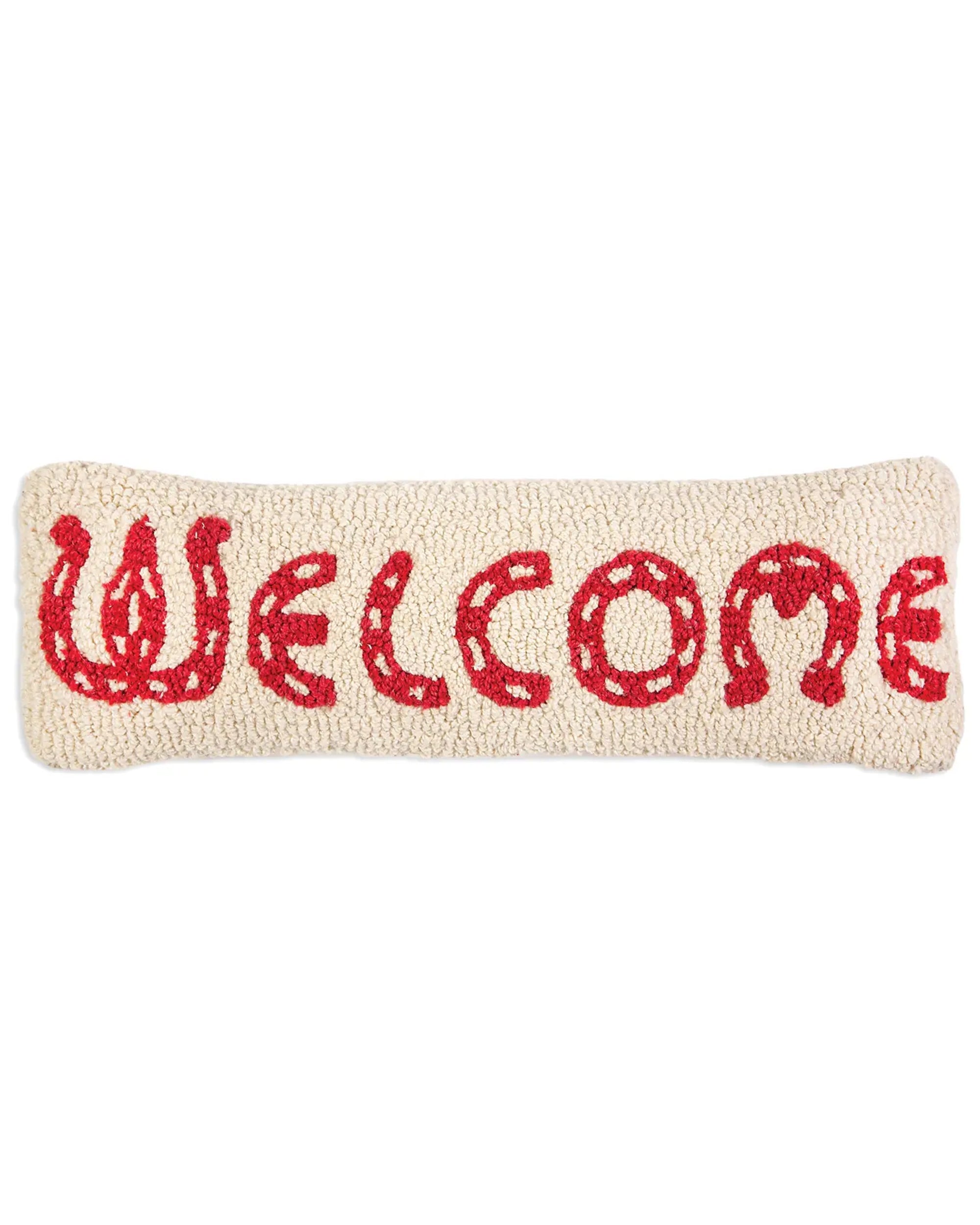 The C4C Horseshoe Welcome Pillow by Faire is a rectangular, cream hand-hooked wool pillow featuring “WELCOME” stitched in red with horseshoe accents on each letter.
