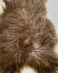 A close-up of the Faire Icelandic Sheepskin rug showcases its long, fluffy, wavy hair spread across a light textured surface.