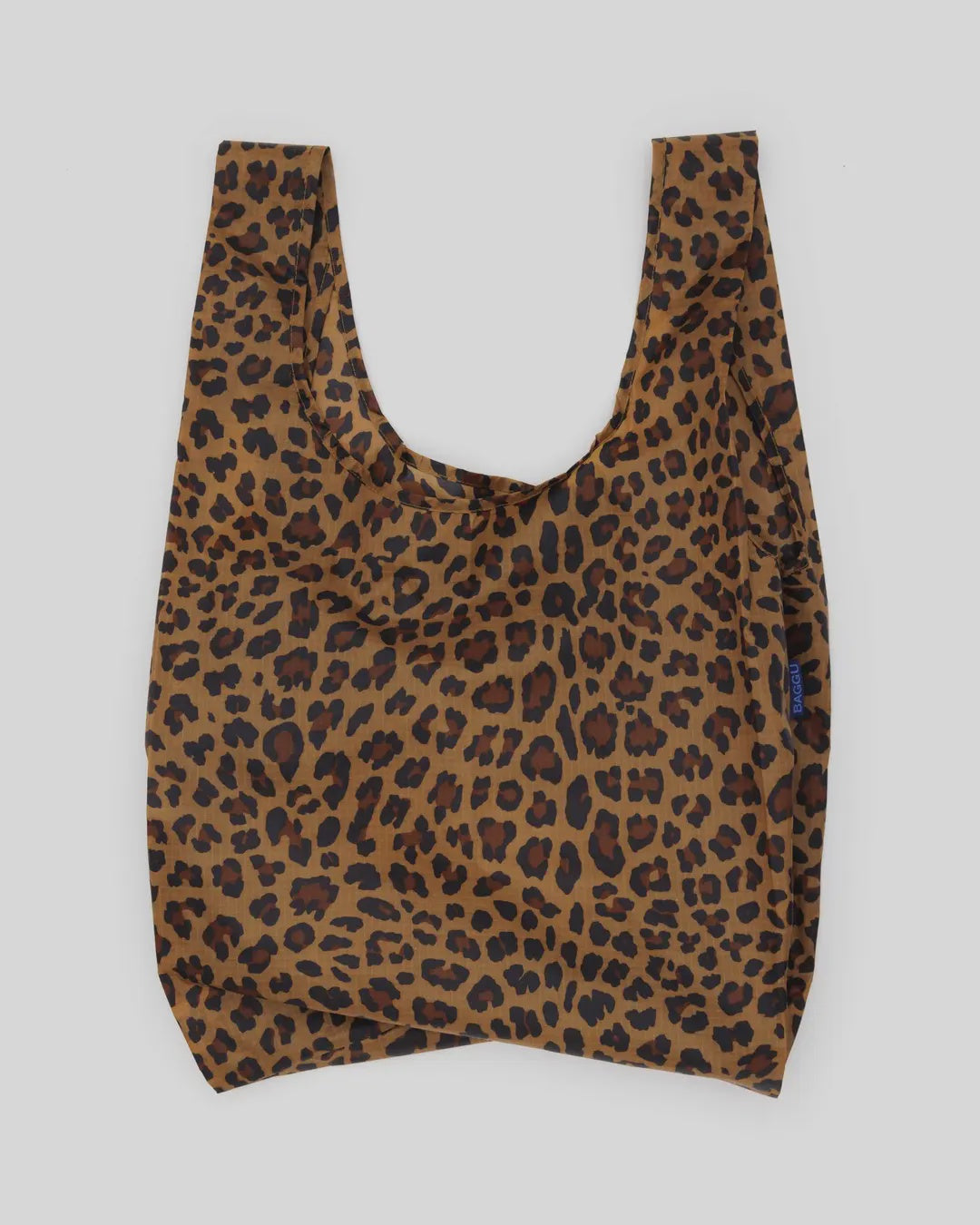 The Baggu Standard by Baggu is a chic, machine-washable reusable shopping bag made from recycled ripstop nylon. It features a leopard print on a plain gray background and has a wide opening with short handles for convenience.