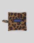 The Baby Baggu, a leopard print foldable bag by Baggu, crafted from recycled ripstop nylon with "BAGGU" on a blue tag, is set against a plain light grey background. This practical and stylish reusable shopping bag is machine washable for easy care.