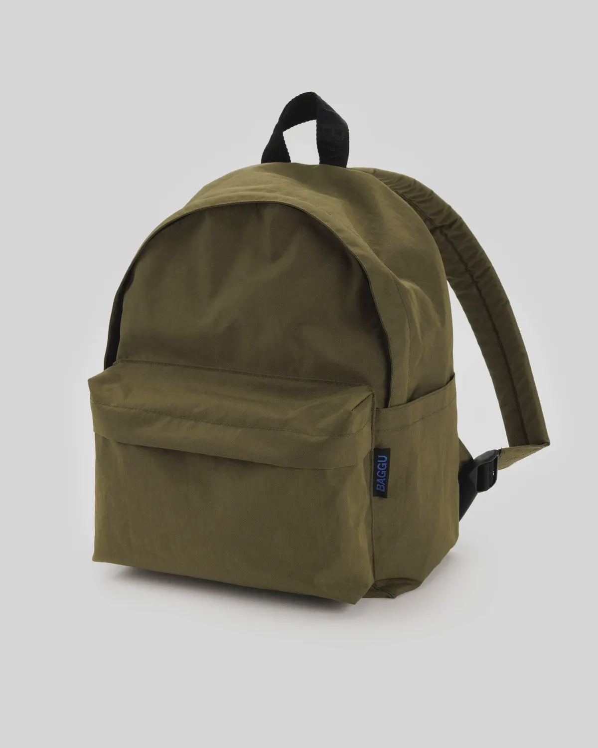 The Baggu Nylon Backpack, a lightweight and durable option, features a large main compartment and front pocket. It includes adjustable shoulder straps, a black handle, an interior laptop sleeve, and comes in green with a minimalist design on a plain gray background.