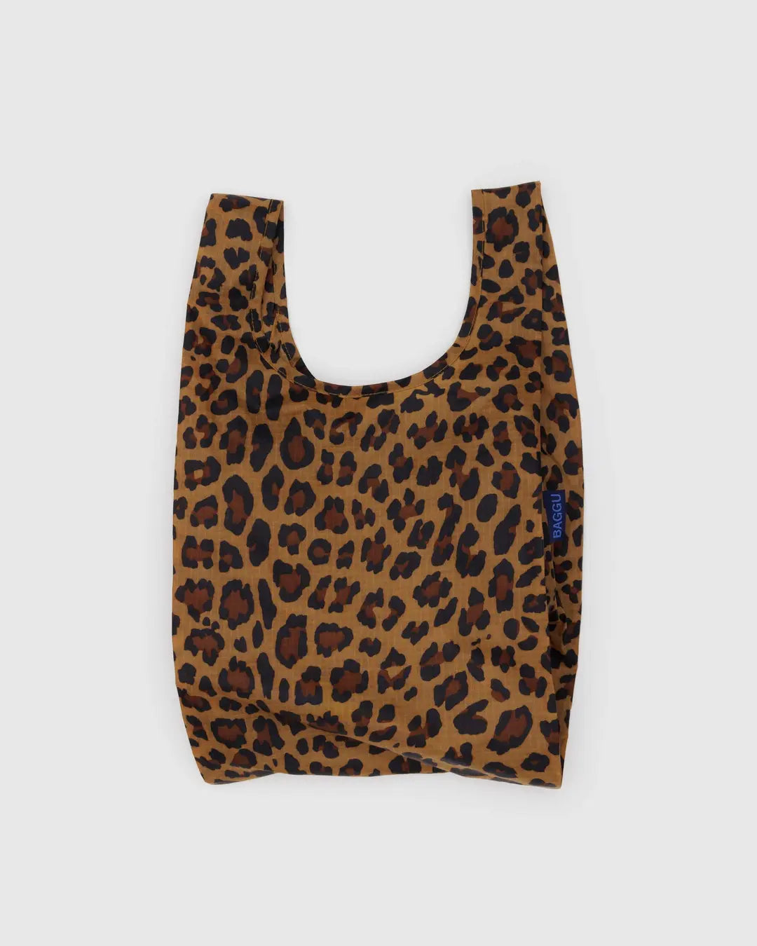 The Baby Baggu by Baggu is a reusable shopping bag made from recycled ripstop nylon in a chic leopard print. It features black and dark orange spots on a brown backdrop with a light gray background, a small blue side tag, and is machine washable for stylish practicality.