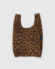 The Baby Baggu by Baggu is a reusable shopping bag made from recycled ripstop nylon in a chic leopard print. It features black and dark orange spots on a brown backdrop with a light gray background, a small blue side tag, and is machine washable for stylish practicality.