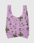 The Baggu Standard by Baggu is a pink reusable bag crafted from recycled ripstop nylon, featuring cartoon drawings of a white dog wearing a green hat. The design includes the pup enjoying tennis and photography amid whimsical cacti and musical notes. It's also machine washable for easy care!.