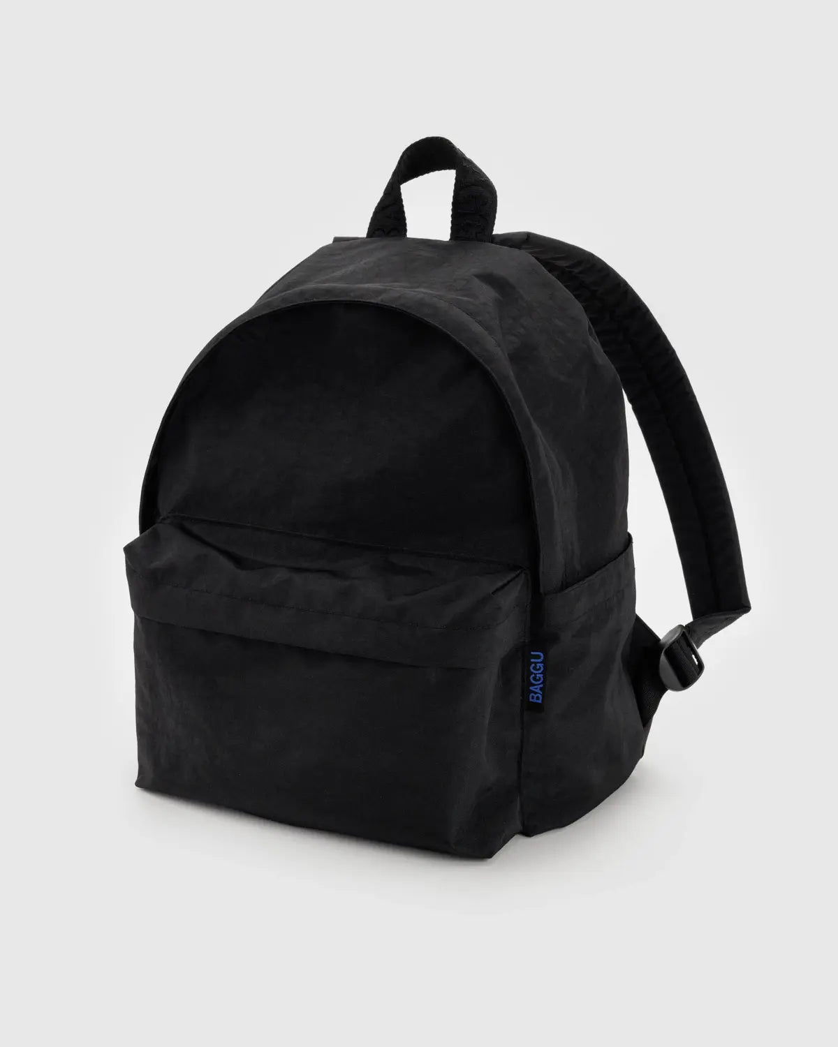 The Baggu Nylon Backpack, crafted from recycled nylon, comes in black with a large main compartment and front pocket. It features adjustable shoulder straps, a small top handle, a laptop sleeve, and its subtle texture with simple design makes it ideal for everyday use.