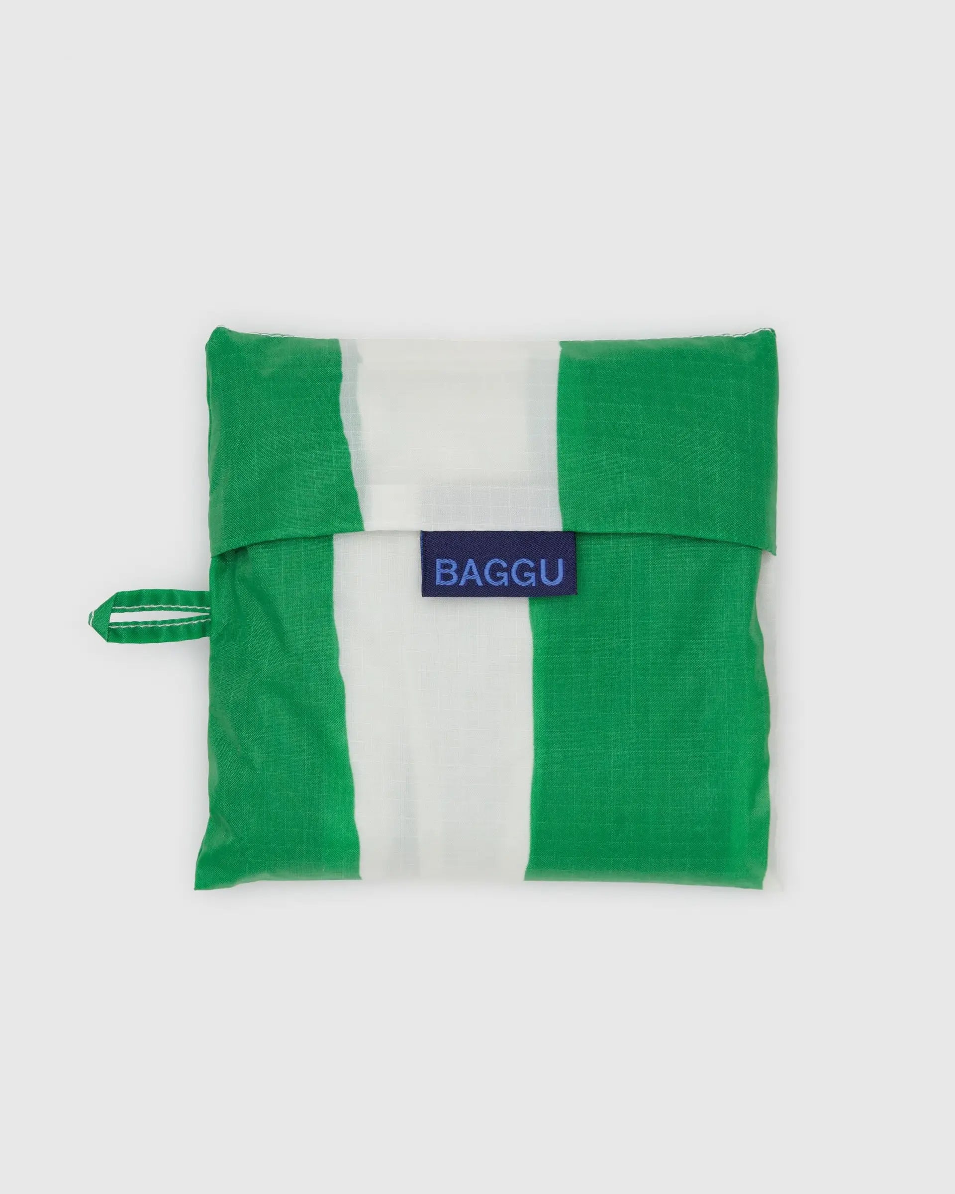 The Big Baggu by Baggu is a reusable shopping bag made from recycled ripstop nylon, folds into a square pouch, and features green and white vertical stripes, a left-side loop, and blue "BAGGU" label—ideal for travel or daily errands.