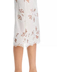 A person wearing the Cissa Summer Pencil Skirt, a white pull-on midi with floral cut-out embroidery, scalloped hem, and elastic waistband, paired with black open-toe heeled sandals.
