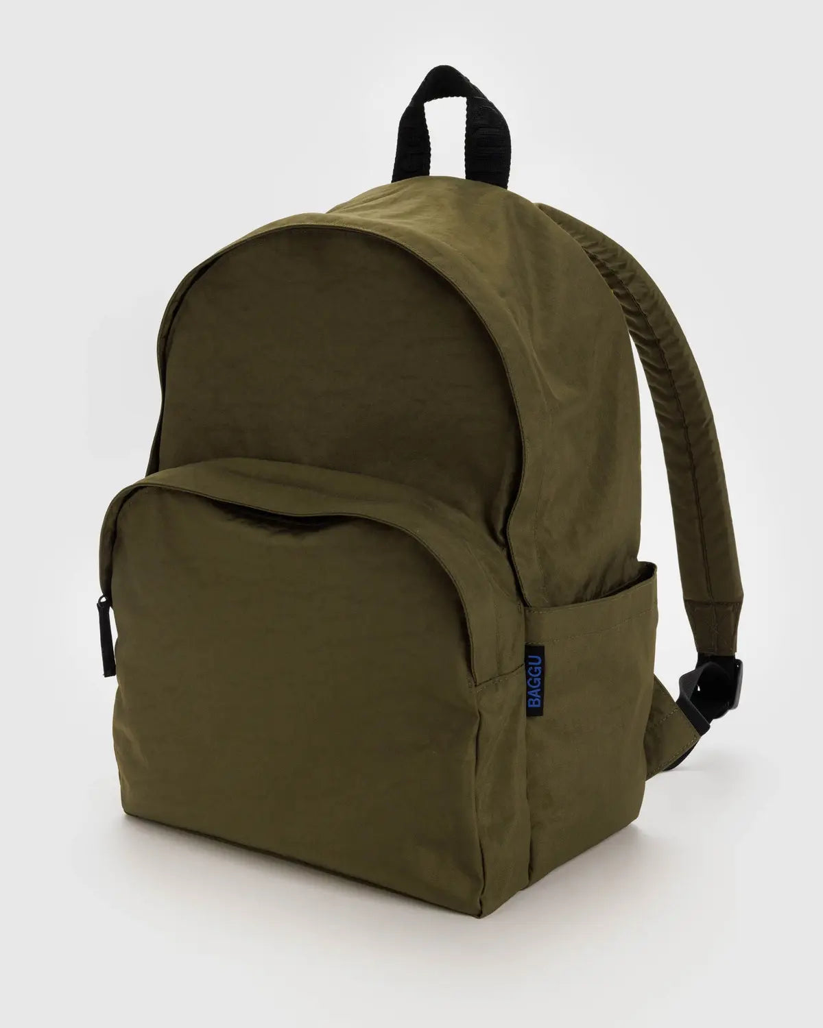 The Baggu Nylon Backpack in olive green is made from recycled nylon and features a large main compartment, front zippered pocket, adjustable padded shoulder straps, and a black top carrying handle with a small blue tag on the side.