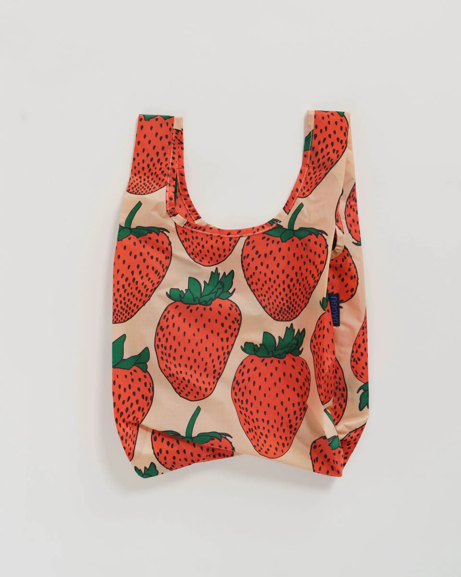 The Baby Baggu by Baggu is a reusable shopping bag made from recycled ripstop nylon, featuring a beige background with red strawberries and green leaves. Machine washable, it combines practical use with a playful design.