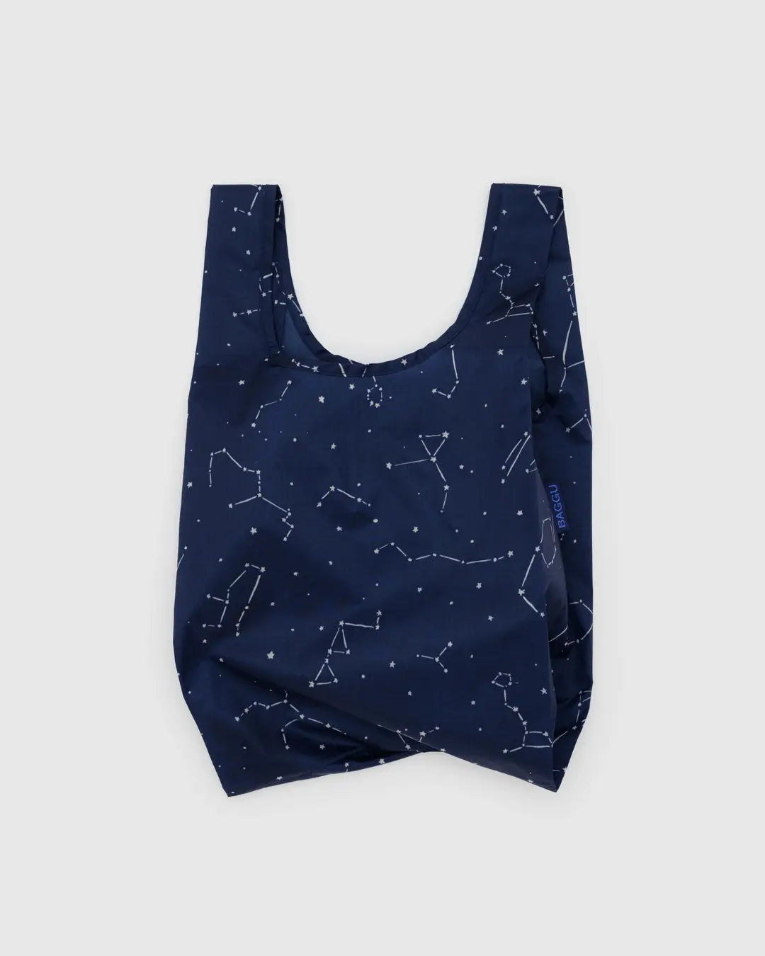 The Baby Baggu by Baggu is a navy blue, reusable shopping bag made from recycled ripstop nylon with white constellation patterns. Displayed against a light gray backdrop, this machine-washable tote combines style with eco-friendliness.