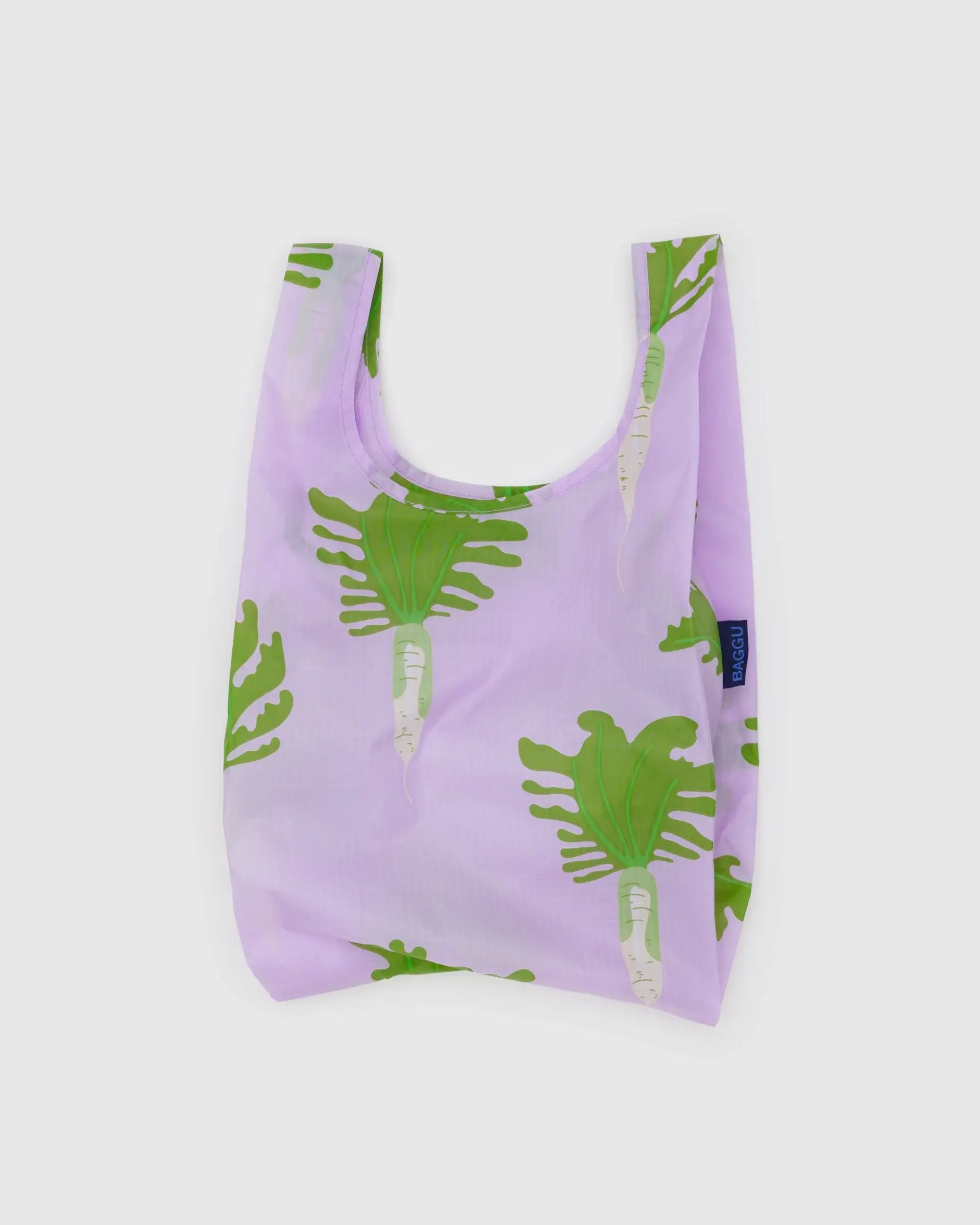 The Baggu Baby Baggu is a reusable shopping bag made from recycled ripstop nylon. It features a light purple background with a green radish pattern, has two handles, and is shown against a plain white surface.