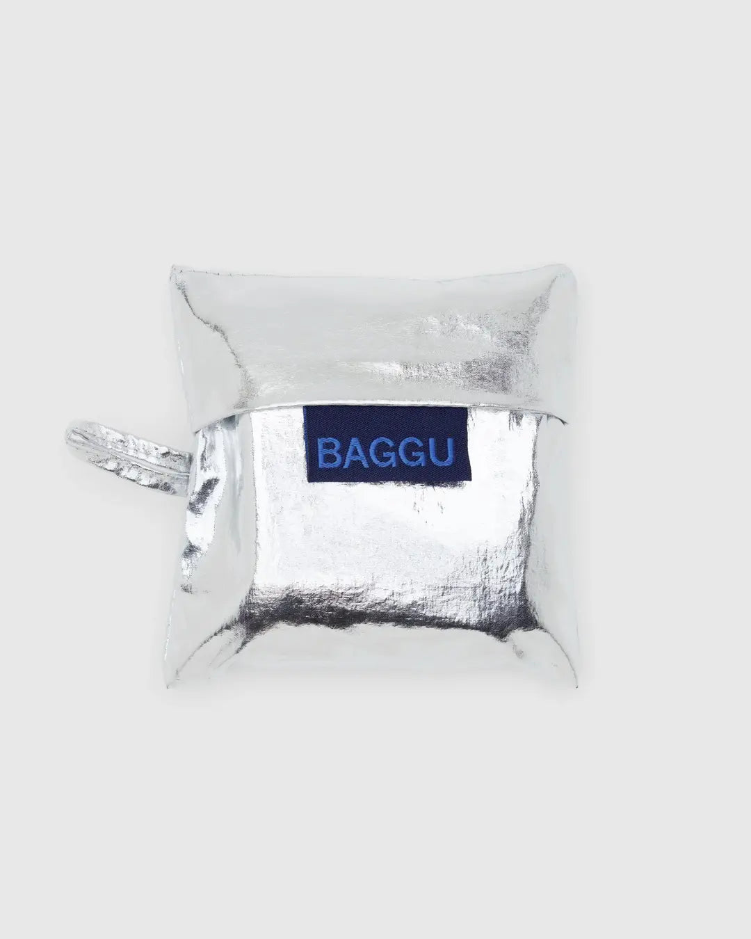 The Baby Baggu Metallic Silver by Baggu is a shiny, silver metallic pouch made from 100% recycled nylon, featuring a loop handle and a blue patch with "BAGGU" in white. It's machine washable and showcased on a light gray background.