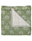 The Jeeva Sage Quilt by John Robshaw features a folded sage green design with bold blue florals, plus a white underside with a small leafy motif—an ideal choice for adding floral bedding charm to any space.