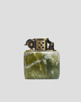 The MENS Kerosene Jade Lighter from Curated Basics features a green marbled stone base complemented by a solid brass top, highlighting intricate details and a circular hole pattern on its metal section.