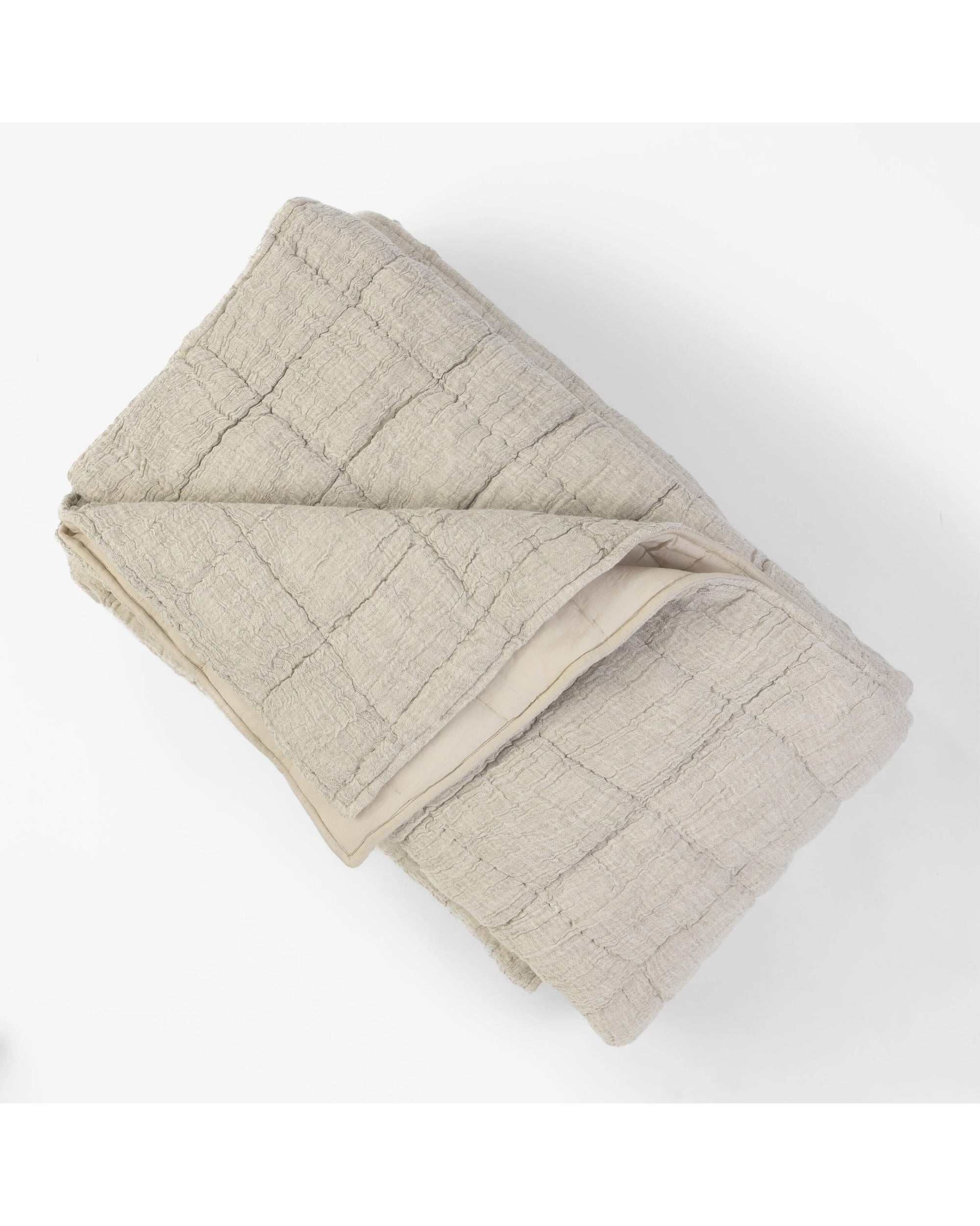 The Johnston Quilt Queen by Amity Home is a light beige, cotton/linen blend quilt with a subtle hand-quilted block pattern, neatly folded and displayed on a white background.