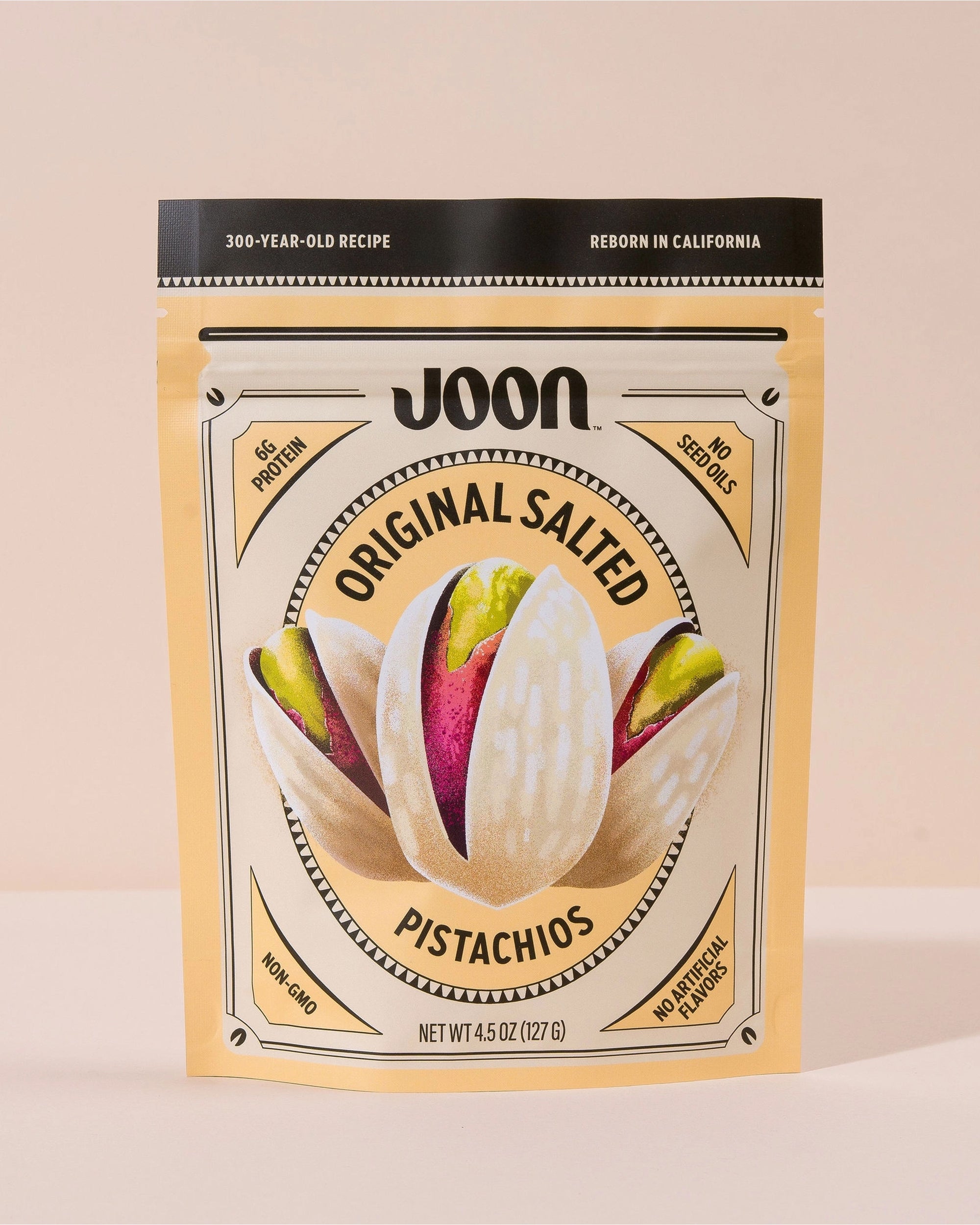 A beige resealable bag of Faire Joon Pistachios features an illustrated pistachio and highlights 6g protein, non-GMO, no artificial flavors, and no seed oils for a pure snacking experience.