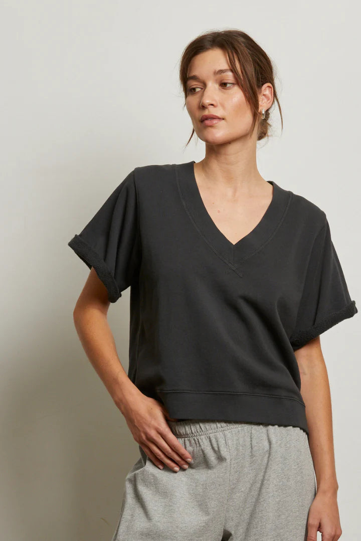 A woman wearing the Perfectwhitetee French Terry SS Crew and light gray sweatpants stands against a neutral background, looking relaxed. The cozy French terry material adds comfort to her laid-back style.