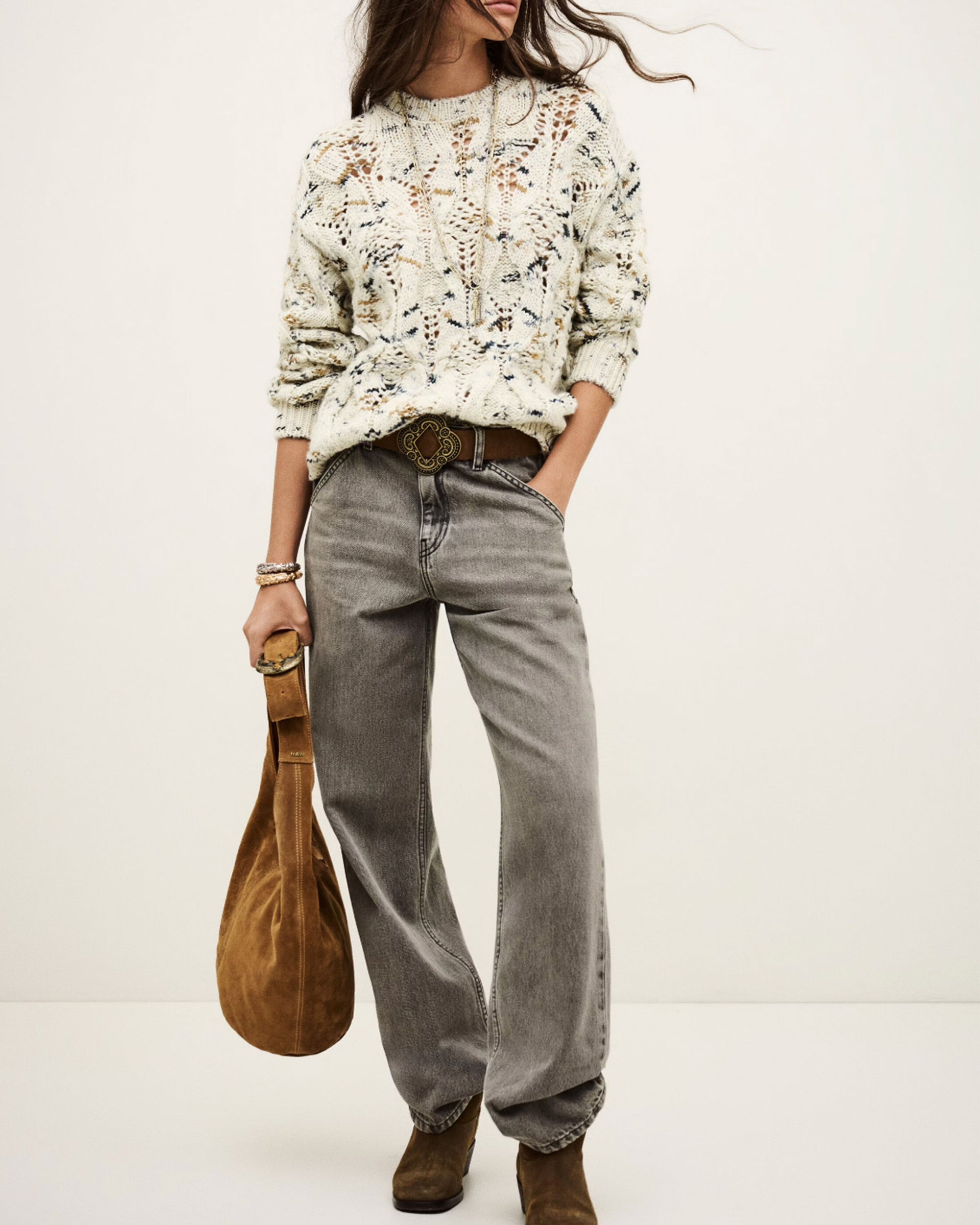 Wearing the Jumper Rave by BA&SH—a textured cream 100% wool sweater—styled with loose gray jeans, a brown belt, brown boots, and a brown suede bag, standing against a light background. Hand wash or dry clean recommended.