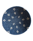 The Kabaya Large Bowl by Amsha - Faire is a round Rwandan basket featuring a dark blue spiral pattern with small white geometric designs evenly spaced around the sides, shown from above on a white background.