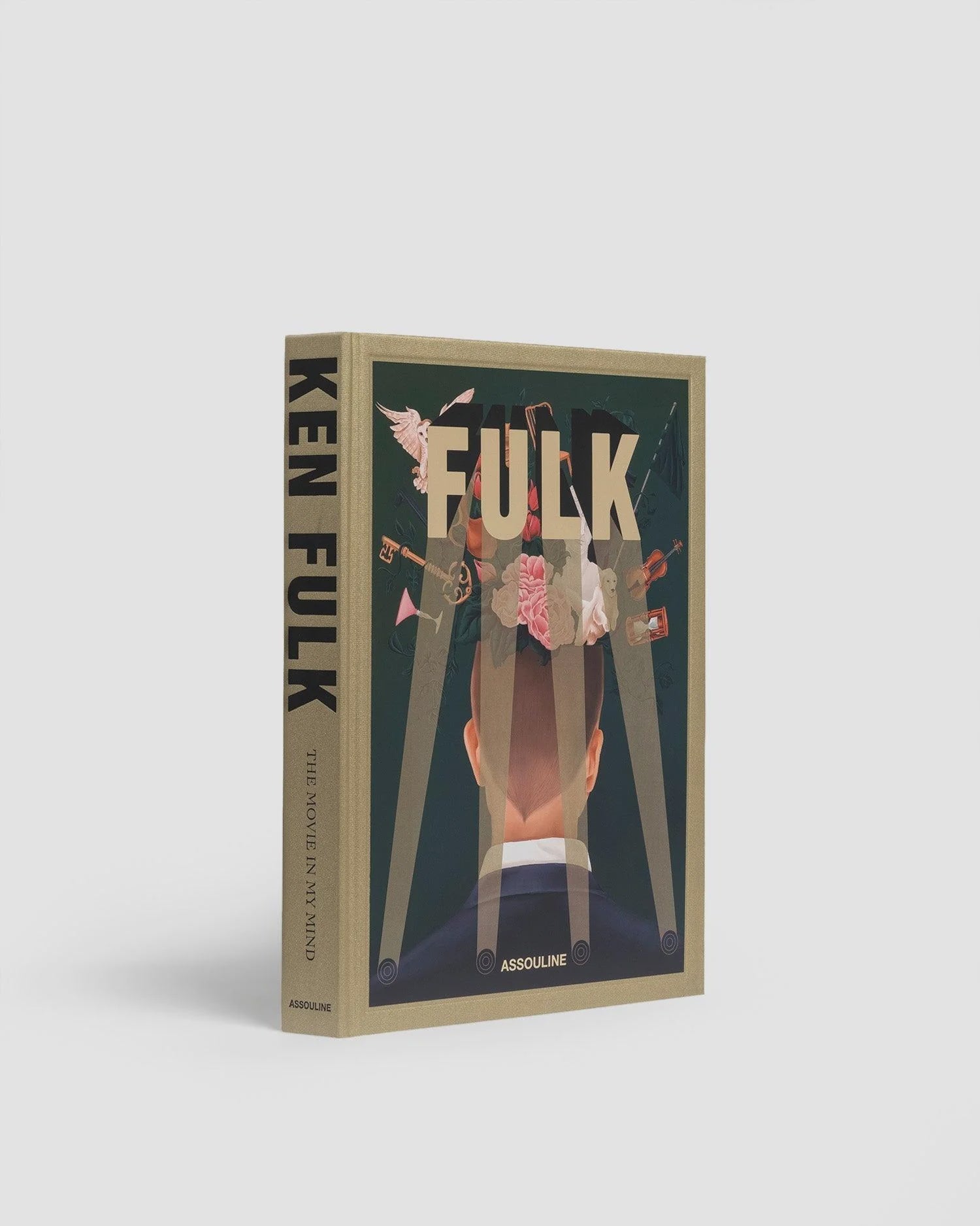 A book titled "Columbia 100th Anniversary" published by Assouline. Renowned interior designer Ken Fulk brings his cinematic flair to life with a cover depicting an illustrated head, seen from behind, overflowing with objects like flowers, hands, and mirrors. The spine prominently displays the title and author's name.