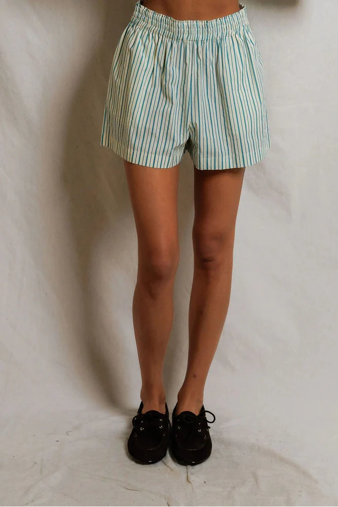 A person models the Perfectwhitetee Julie Poplin Short—structured cotton shorts with light blue and white stripes—paired with black shoes, shown from the waist down against a plain white background.