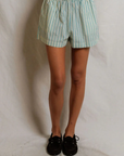A person models the Perfectwhitetee Julie Poplin Short—structured cotton shorts with light blue and white stripes—paired with black shoes, shown from the waist down against a plain white background.